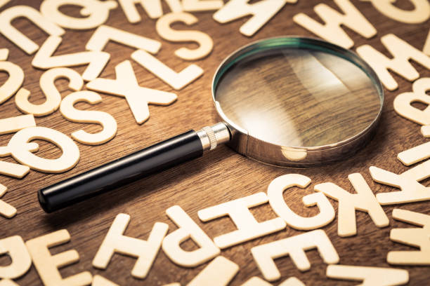 Magnifying glass with many wood letters of English alphabets, searching words to communicate, learning English concept
